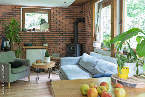 Interior of living room in cozy cottage with natural wood, design furniture and brick wall.