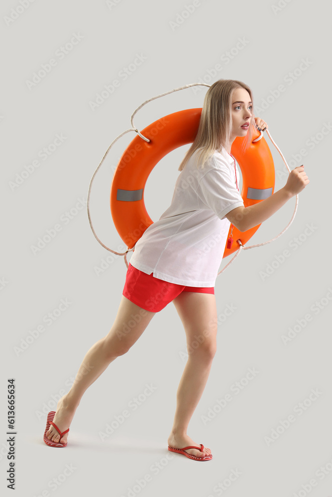 Female lifeguard with ring buoy running on light background Female lifeguard with ring buoy running on light background