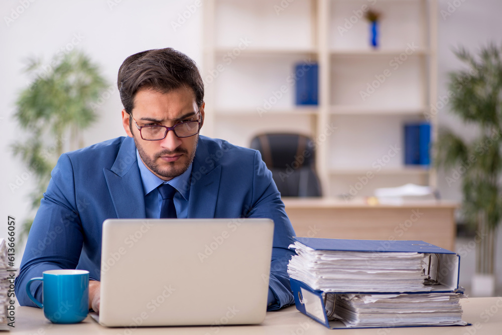 Young male employee and too much work in the office Young male employee and too much work in the office