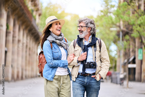 Happy older couple having fun walking outdoors in city. Retired people enjoying a sightseeing walk on street in spring. Mature couple relationships and vacations of pensioners. photo