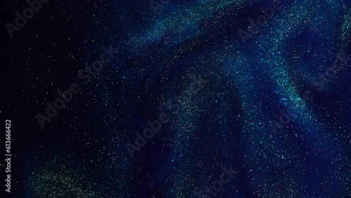 Bursting Gold Dust Particles in Blue Liquid. Abstract moving gold sparkling particles in blue fluid with green tints. Abstract luxe background of Shiny Floating Golden Dust Movement.