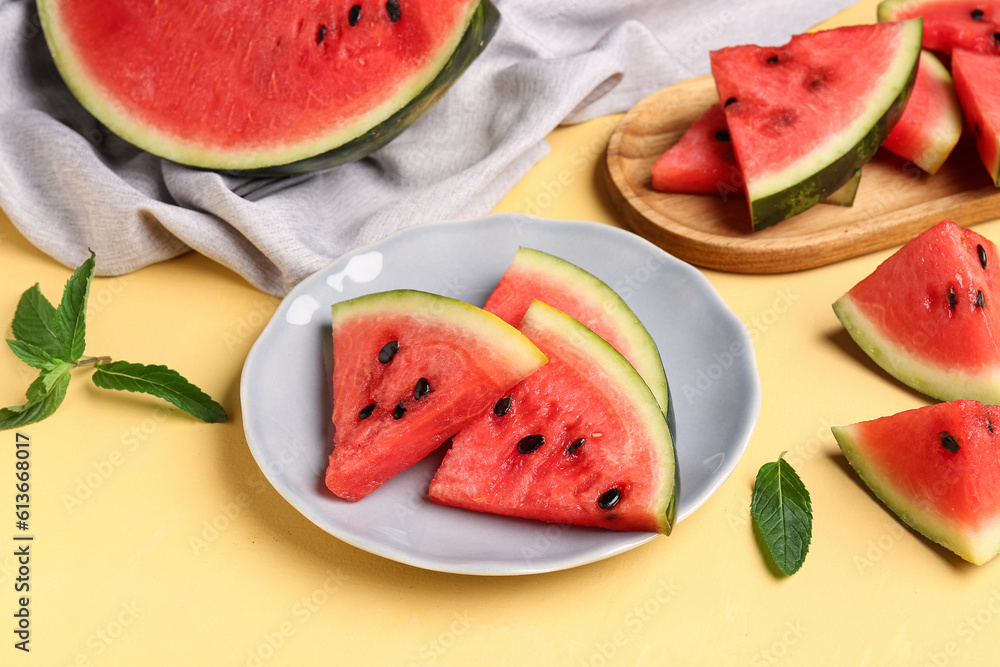 Plate and board with pieces of fresh watermelon on yellow background