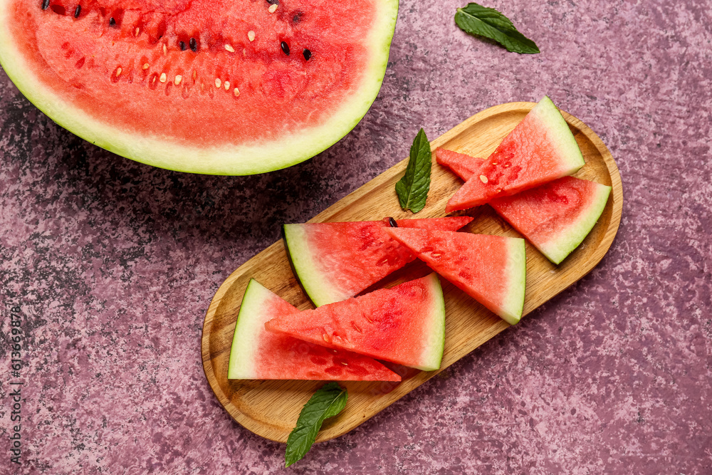 Half of fresh watermelon and board with pieces on purple background Half of fresh watermelon and board with pieces on purple background