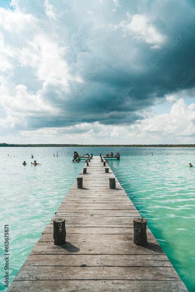 Wide shot showing pier leading to a fresh water blue lagoon in Bacalar, Mexico.