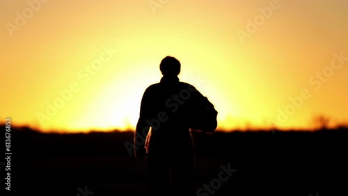 A Jet Pilot Walking holding His Flying Helmet at Air Base at Sunset. 4K Resolution. photo