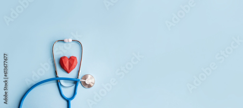 Blue stethoscope and red polydiagonal decorative heart on pastel background. Medical banner. Doctor's day concept. Selective focus, copy space
