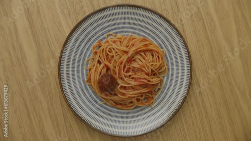 top view of plate of pasta in tomato sauce rotating with a meatball