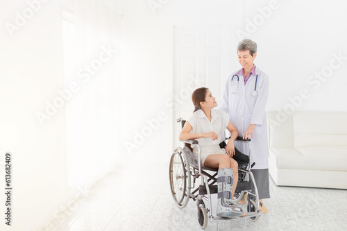 Asian patient sitting on wheelchair, patient wear air cast walking boot, doctor and patient talk about symptoms and treatment plan, rehabilitation activity