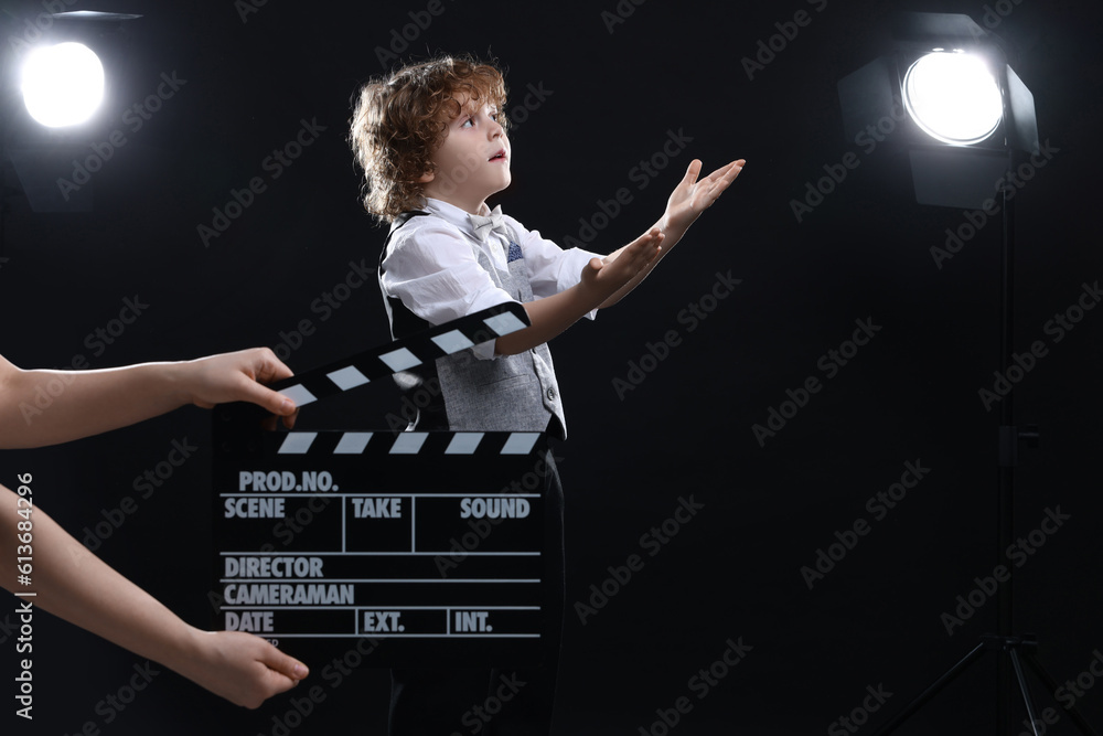 Cute boy performing while second assistant camera holding clapperboard