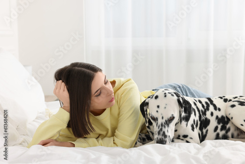 Beautiful woman with her adorable Dalmatian dog on bed at home. Lovely pet