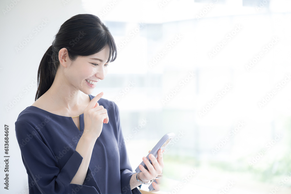 スマホを見て笑顔な美しい人 見つけるや検索のイメージ ビジネスシーンなどに スマホを見て笑顔な美しい人 見つけるや検索のイメージ ビジネスシーンなどに