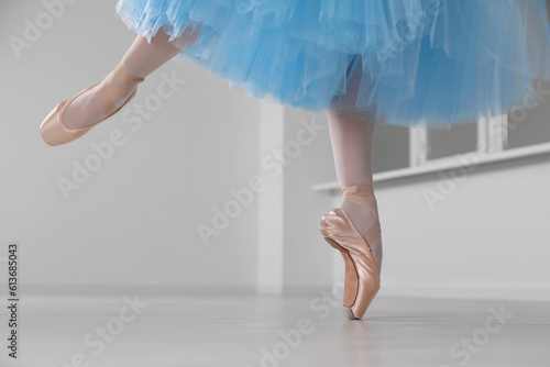 Ballerina in pointe shoes and light blue skirt dancing indoors, closeup