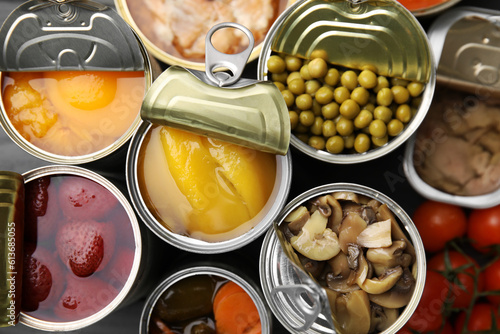 Open tin cans with different products as background, top view