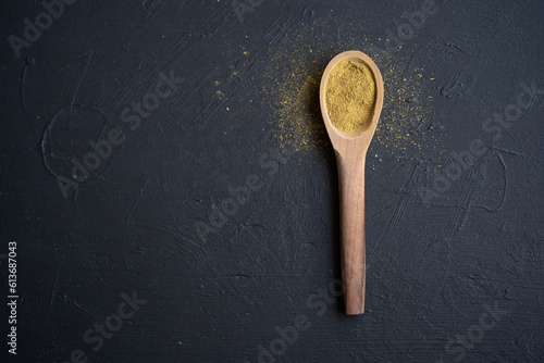 cuchara de madera con orégano en polvo sobre base de madera negra con espacio para texto © AnaPliego