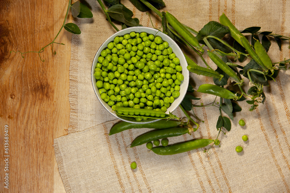 A bowl of appetizing green peas on a linen napkin. Top view.