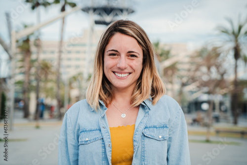 Fotografija Individual portrait of happy blonde young adult woman standing outside with friendly and optimistic expression