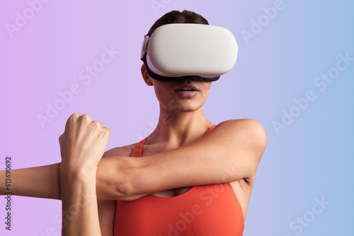 Athletic lady stretching arms while experiencing virtual reality in headset