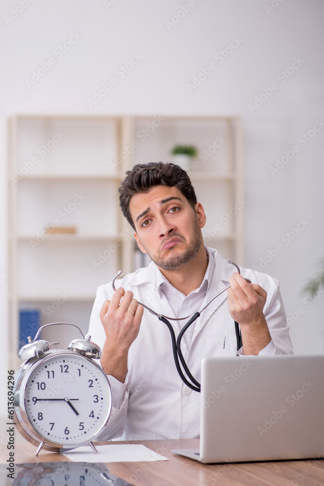 Young male doctor in time management concept Young male doctor in time management concept