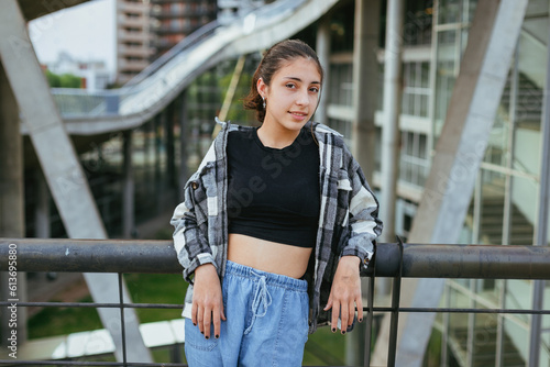 teenage woman resting on a railing looking at the camera in the city