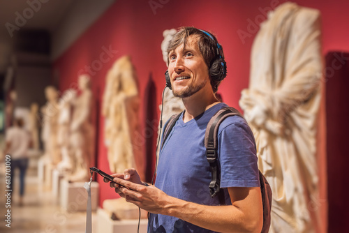 Obraz na płótnie Portrait of contemporary man looking at sculptures and listening to audio guide at museum exhibition w salonie