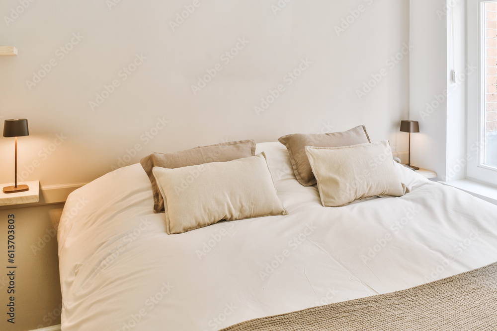 a bed in a bedroom with two pillows on it and a lamp next to the headboard that is lit