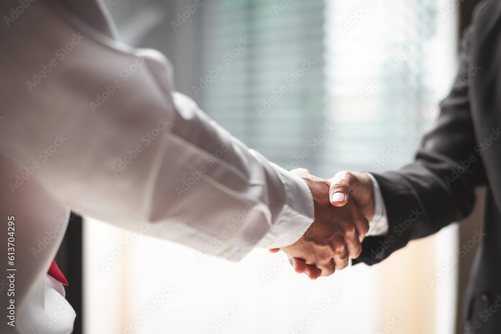 Close up of two business people shaking hands while sitting at the working place