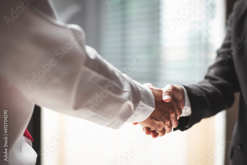 Close up of two business people shaking hands while sitting at the working place photo