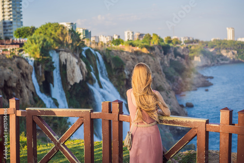 Beautiful woman with long hair on the background of Duden waterfall in Antalya. Famous places of Turkey. Lower Duden Falls drop off a rocky cliff falling from about 40 m into the Mediterranean Sea in