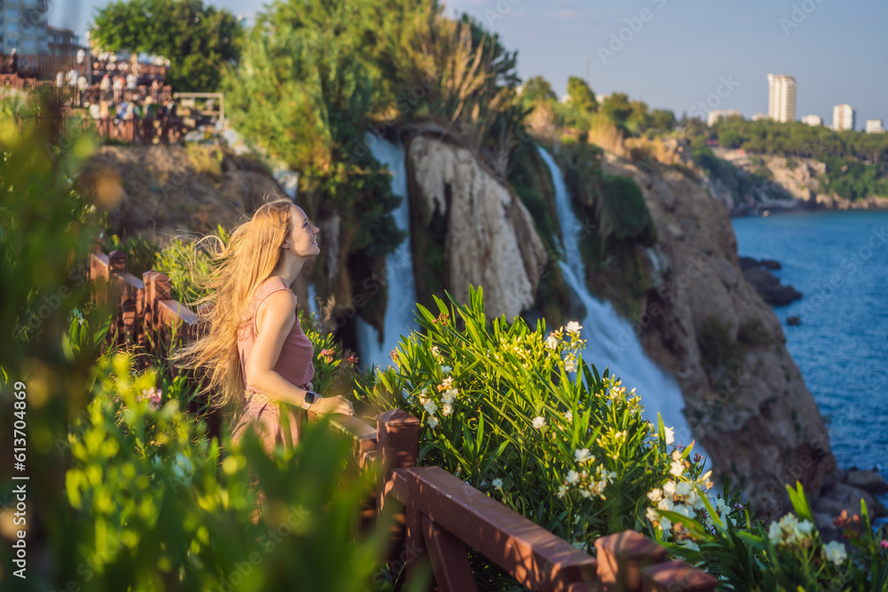 Fototapeta premium Beautiful woman with long hair on the background of Duden waterfall in Antalya. Famous places of Turkey. Lower Duden Falls drop off a rocky cliff falling from about 40 m into the Mediterranean Sea in