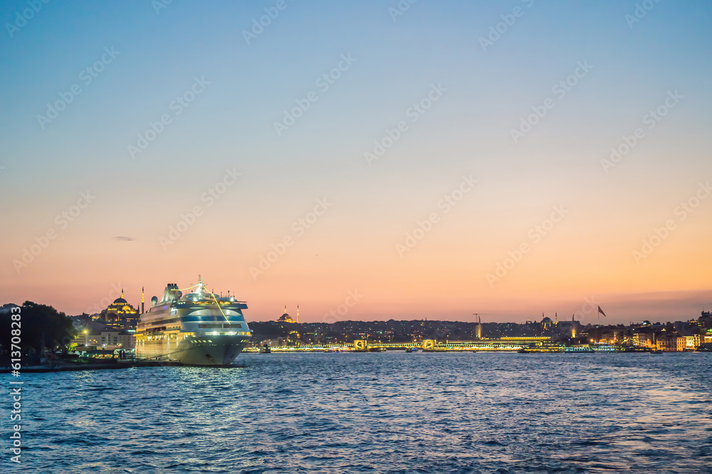 Fototapeta premium Istanbul at sunset, Turkey. Tourist boat sails on Golden Horn in summer. Beautiful sunny view of Istanbul waterfront with old mosque. Concept of travel, tourism and vacation in Istanbul and Turkey