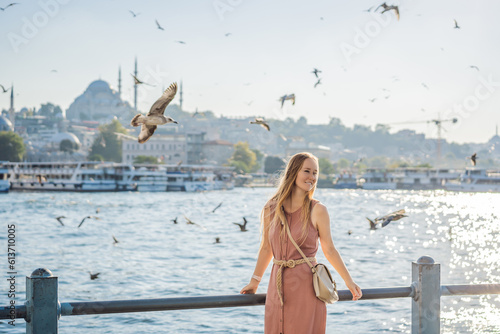 Young woman traveler in pinc dress enjoying great view of the Bosphorus and lots of seagulls in Istanbul photo