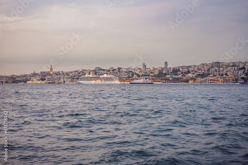 Huge cruise ship docked at terminal of Galataport, located along shore of Bosphorus strait, in Karakoy neighbourhood, with Galata tower in the background