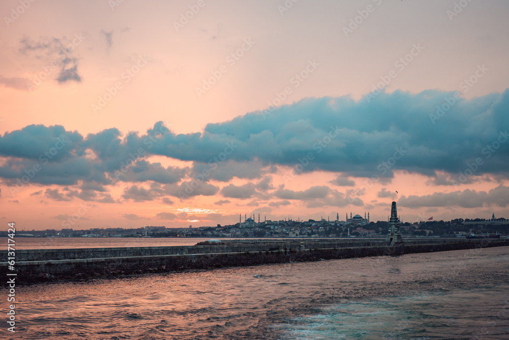 Istanbul at sunset, Turkey. Tourist boat sails on Golden Horn in summer. Beautiful sunny view of Istanbul waterfront with old mosque. Concept of travel, tourism and vacation in Istanbul and Turkey