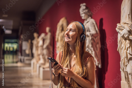 Obraz na plátne Portrait of contemporary young woman looking at sculptures and listening to audi