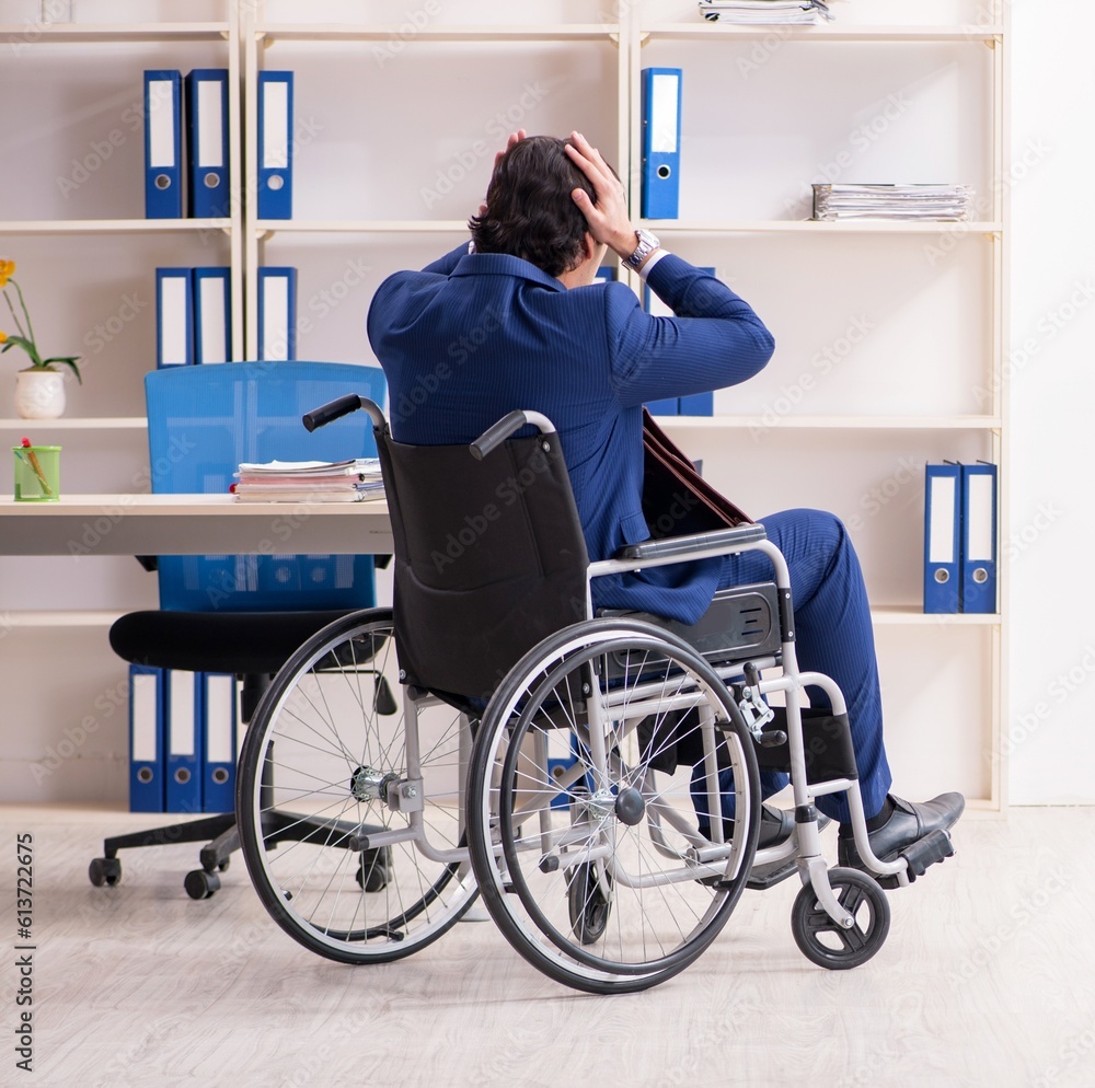 Young male employee in wheelchair working in the office Young male employee in wheelchair working in the office