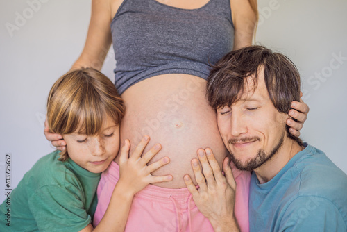 Father and elder son listen to mom's pregnant belly