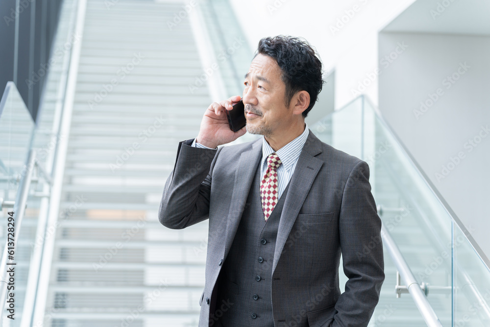 オフィスでスマホで話す中年ビジネスマン(上司・社長・リーダー) オフィスでスマホで話す中年ビジネスマン(上司・社長・リーダー)