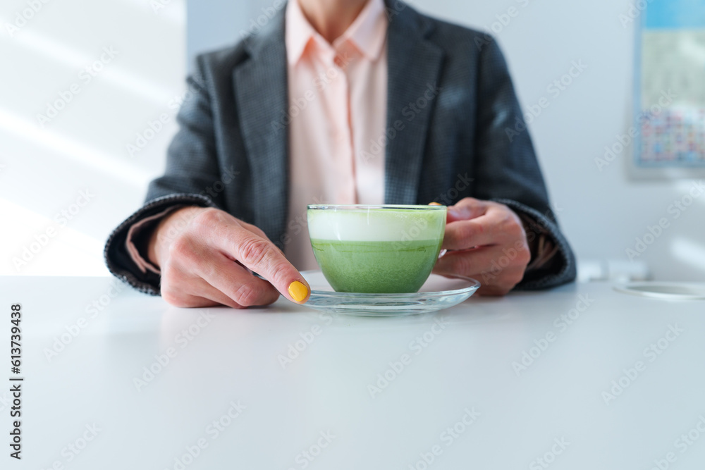 Woman drinks matcha green tea from a transparent cup Woman drinks matcha green tea from a transparent cup