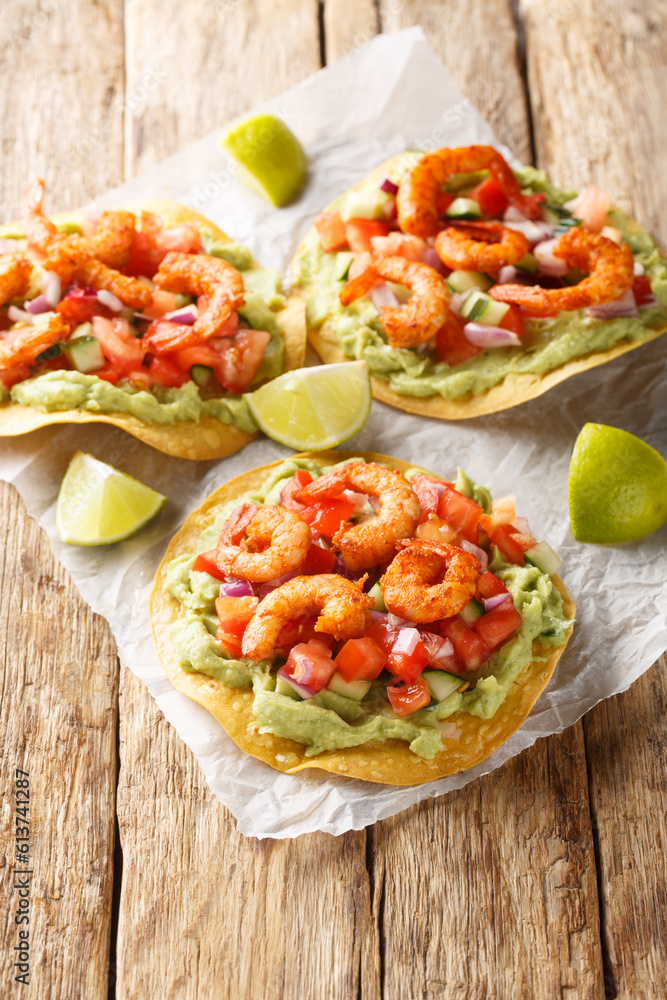 Delicious tostada with shrimps, fresh vegetables and guacamole close-up on a wooden table. Vertical Delicious tostada with shrimps, fresh vegetables and guacamole close-up on a wooden table. Vertical