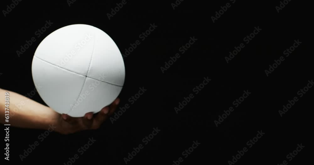 Hand of african american man holding white rugby ball on black background, copy space, slow motion Hand of african american man holding white rugby ball on black background, copy space, slow motion
