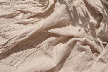 Abstract neutral background, crumpled draped linen fabric texture on sun light with soft shadows, aesthetic sustainable bohemian backdrop, copy space