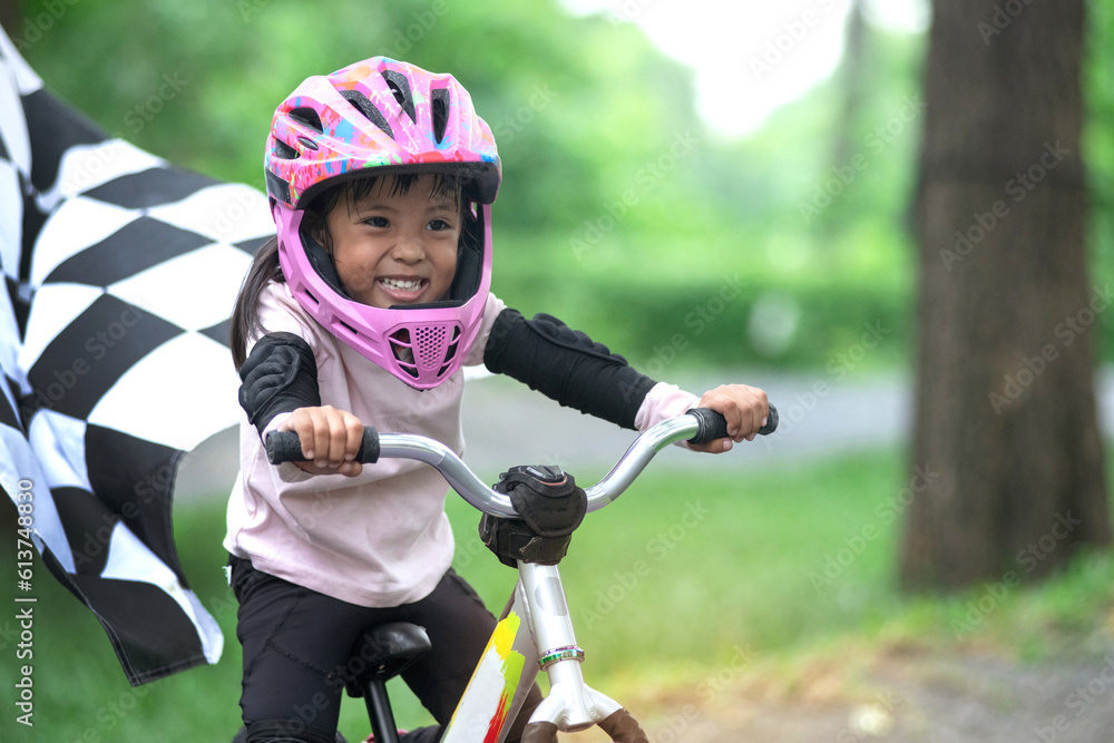 4 years old girl with helmets practicing balance bike, little girl have fun at the pump track, riding through black and white crossed Checkered flag, kids with outdoor sports 4 years old girl with helmets practicing balance bike, little girl have fun at the pump track, riding through black and white crossed Checkered flag, kids with outdoor sports