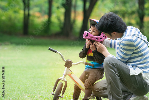 Father or trainer puts on a helmet for safety before practicing, 4 years old girl riding a balance bike, kids with outdoor sports