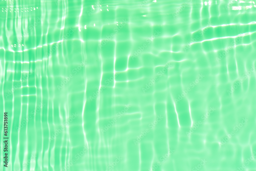 Green water with ripples on the surface. Defocus blurred transparent blue colored clear calm water surface texture with splashes and bubbles. Water waves with shining pattern texture background.