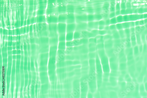 Green water with ripples on the surface. Defocus blurred transparent blue colored clear calm water surface texture with splashes and bubbles. Water waves with shining pattern texture background.