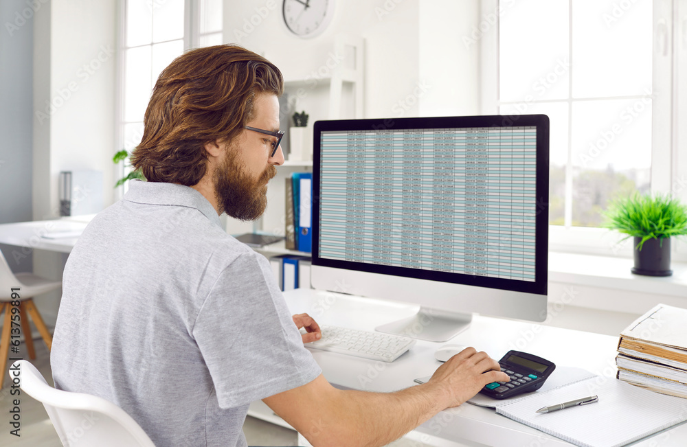 Financial manager calculating about cost and doing finance. Accountant checking financial documents using computer and calculator in office. Audit, tax, accounting and analytical research concept Financial manager calculating about cost and doing finance. Accountant checking financial documents using computer and calculator in office. Audit, tax, accounting and analytical research concept