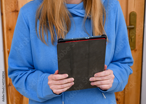 Ruda dziewczyna w niebieskiej bluzie prowadzi wideorozmowę przez tablet 