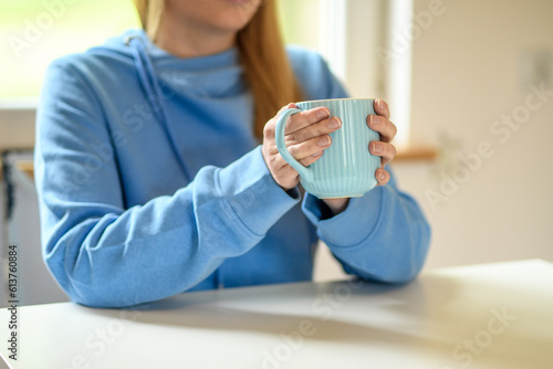 Kobieta siedząca w kafejce trzymająca kubek z herbatą 