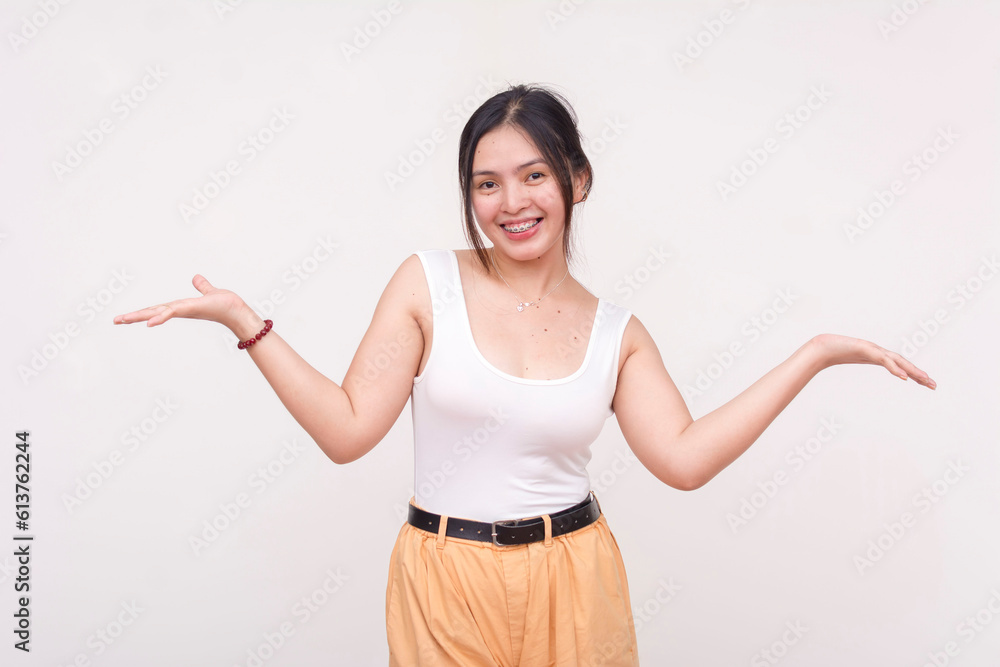 A happy young Asian woman with braces and toothed smile casually shrugging. Isolated on a white background. A happy young Asian woman with braces and toothed smile casually shrugging. Isolated on a white background.