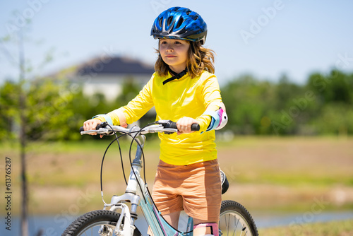 Child riding bicycle. Little kid boy in helmet on bicycle along bikeway. Happy cute little boy riding bicycle in summer park. Child in protective helmet for bike cycling on bicycle. Kid riding bike.